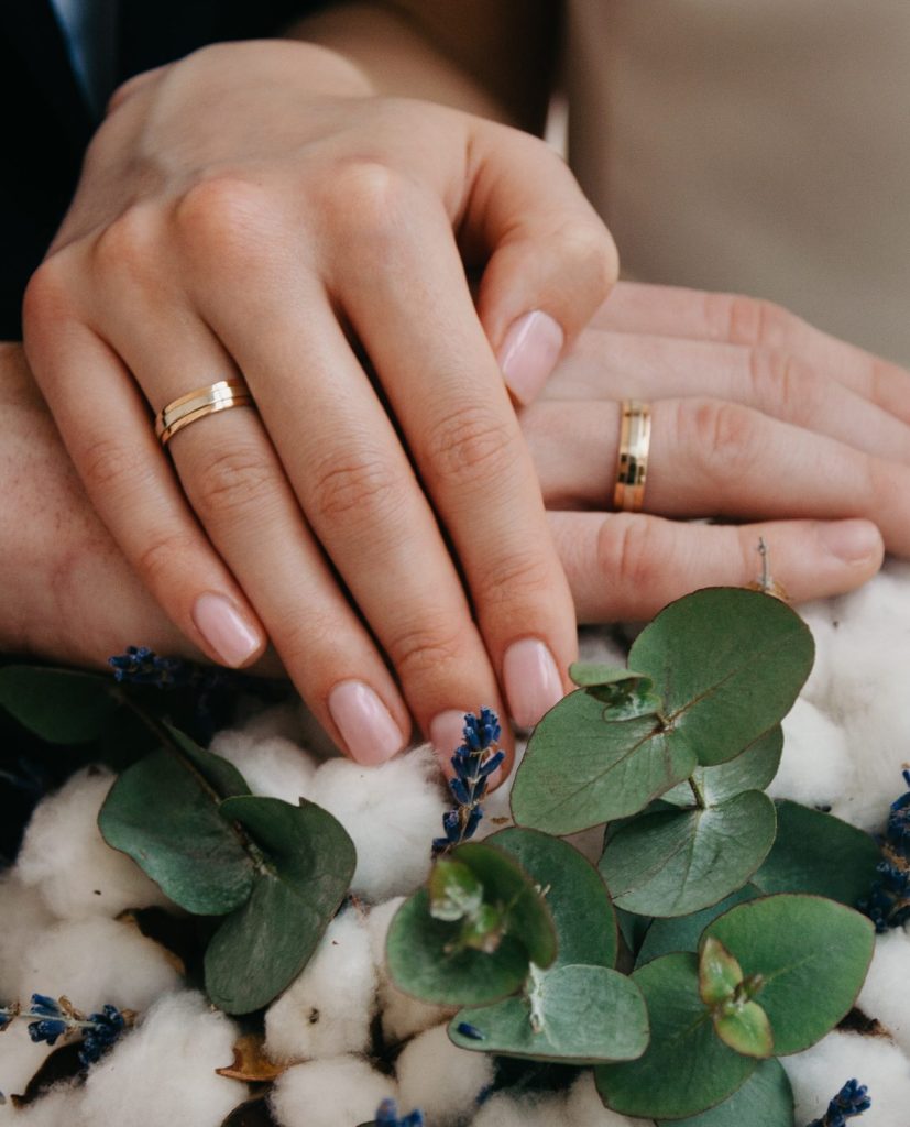 Couple with Gold Wedding Bands Holding Hands on Flowers